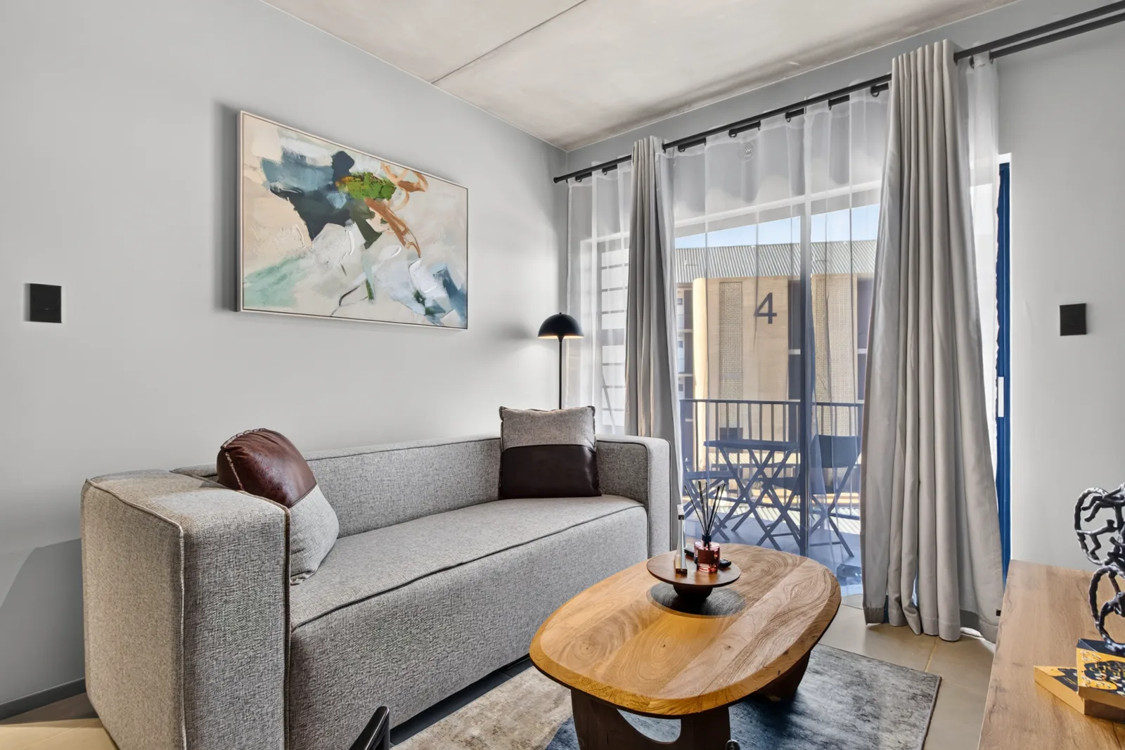 Living room sofa beneath a canvas, balcony doors beyond