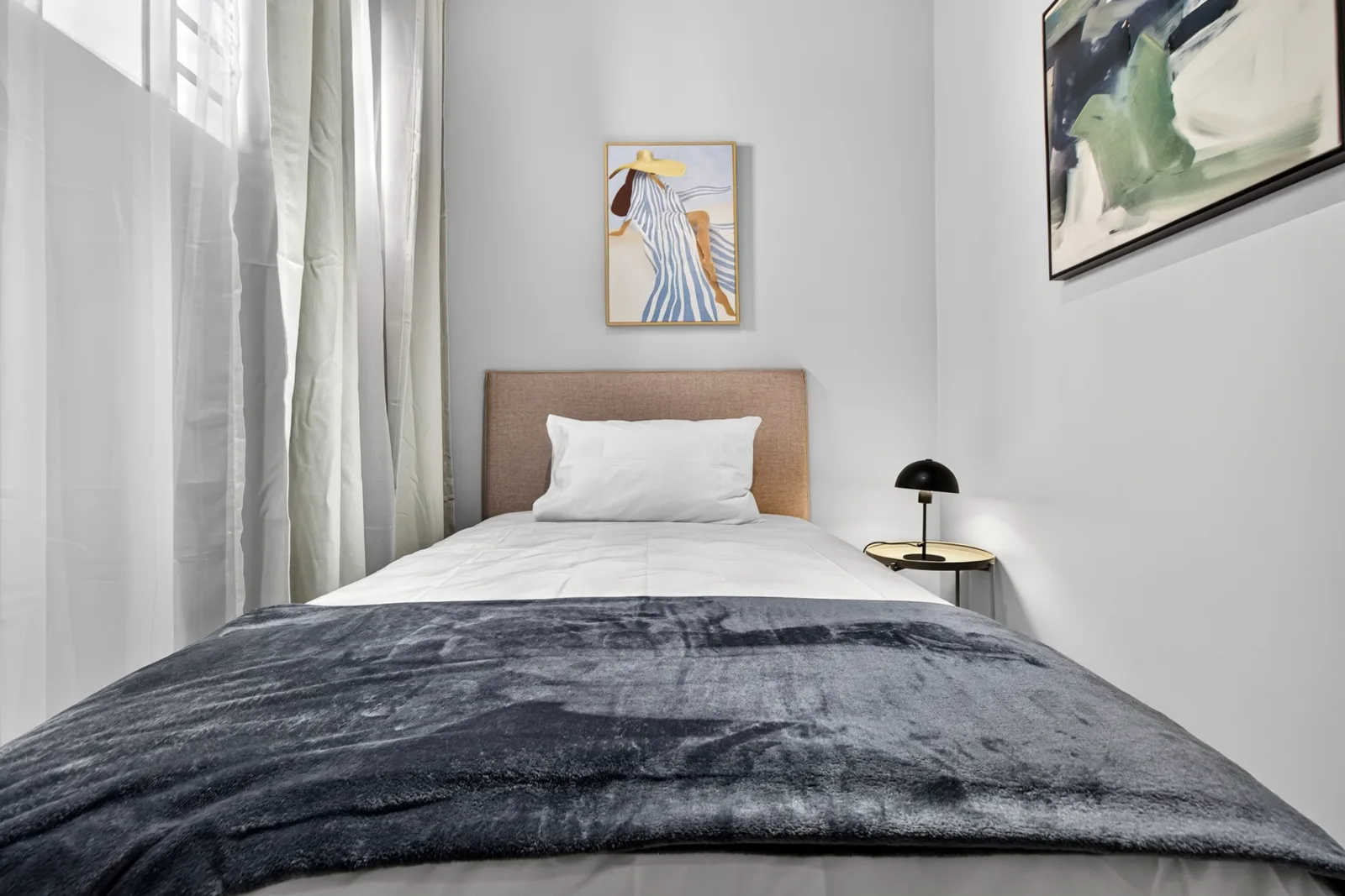 Second bedroom bed beneath framed artwork